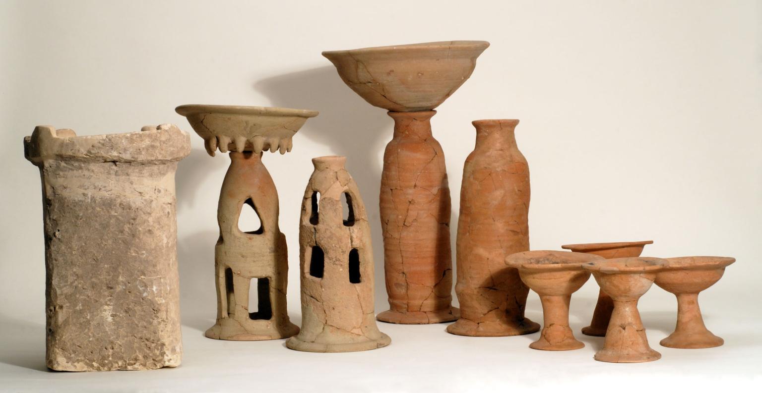 Ritual containers including stone altar, two offering bowls on tall bases, four chalices, and two stands with cylindrical bases. 