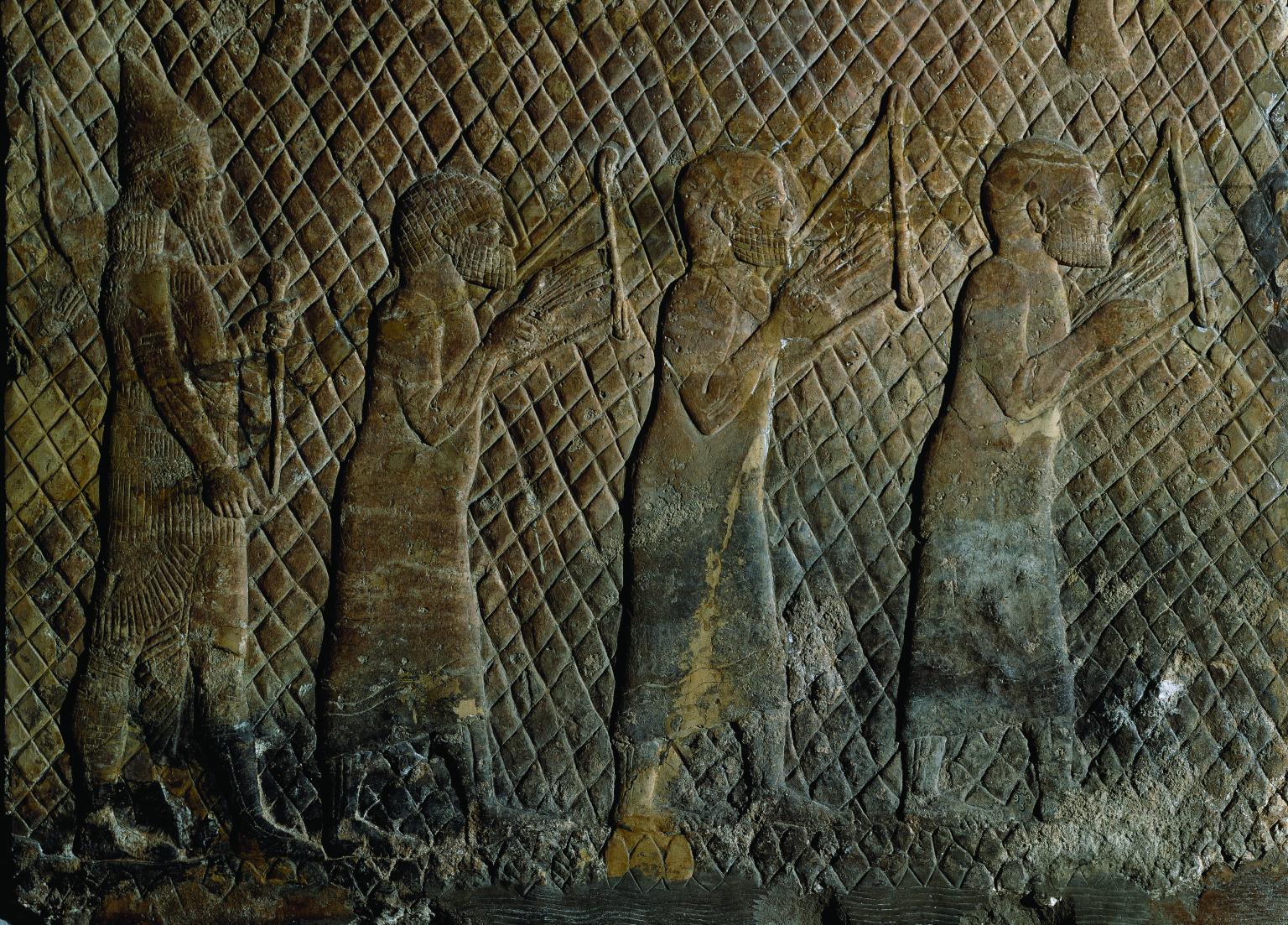 Wall relief showing three bare-headed musicians in tunics holding stringed instruments against their chests, with bearded soldier holding weapon behind them.