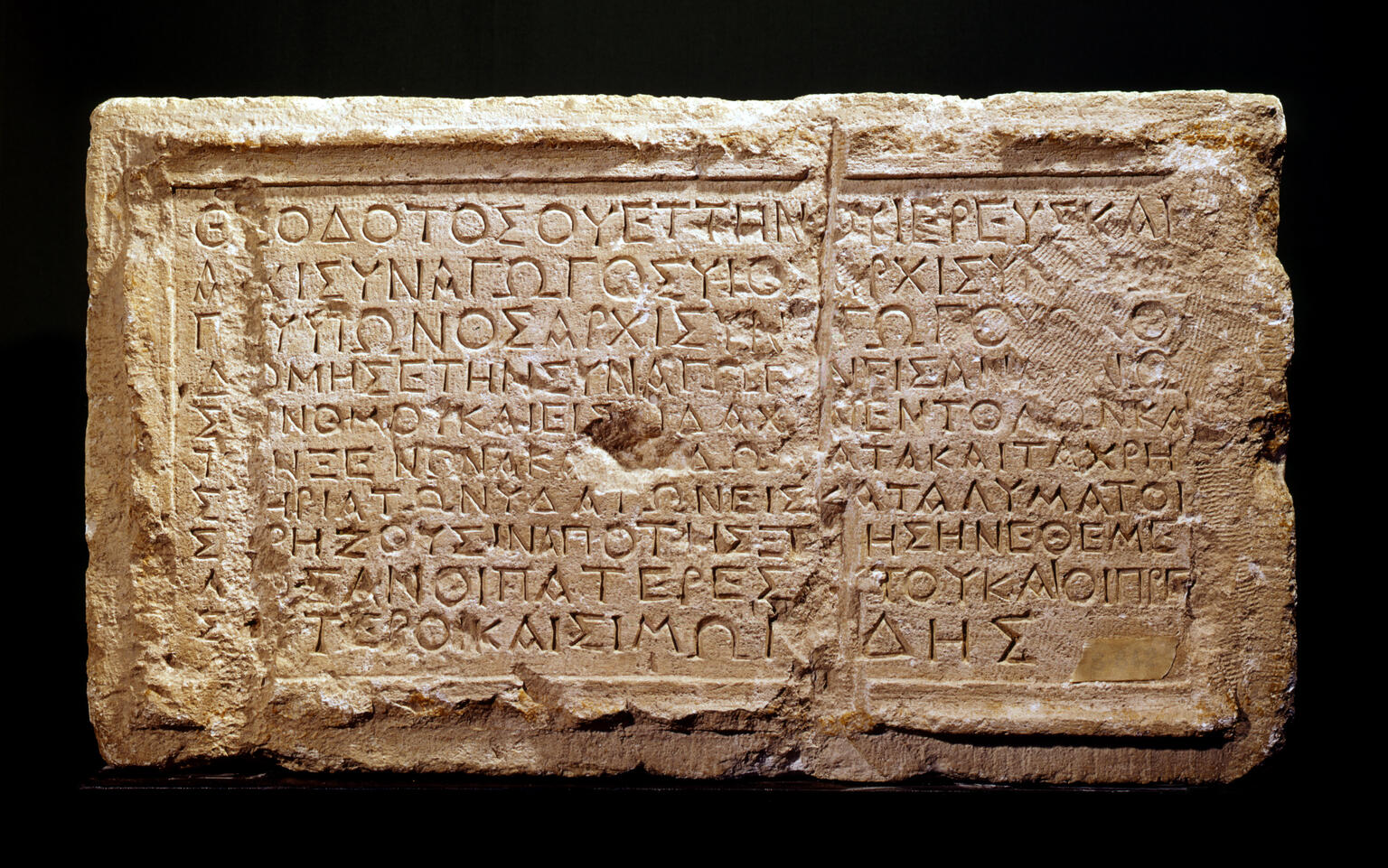 An ancient rectangular stone tablet engraved with Greek text, featuring clear, deeply carved letters and some signs of wear and erosion on the surface.