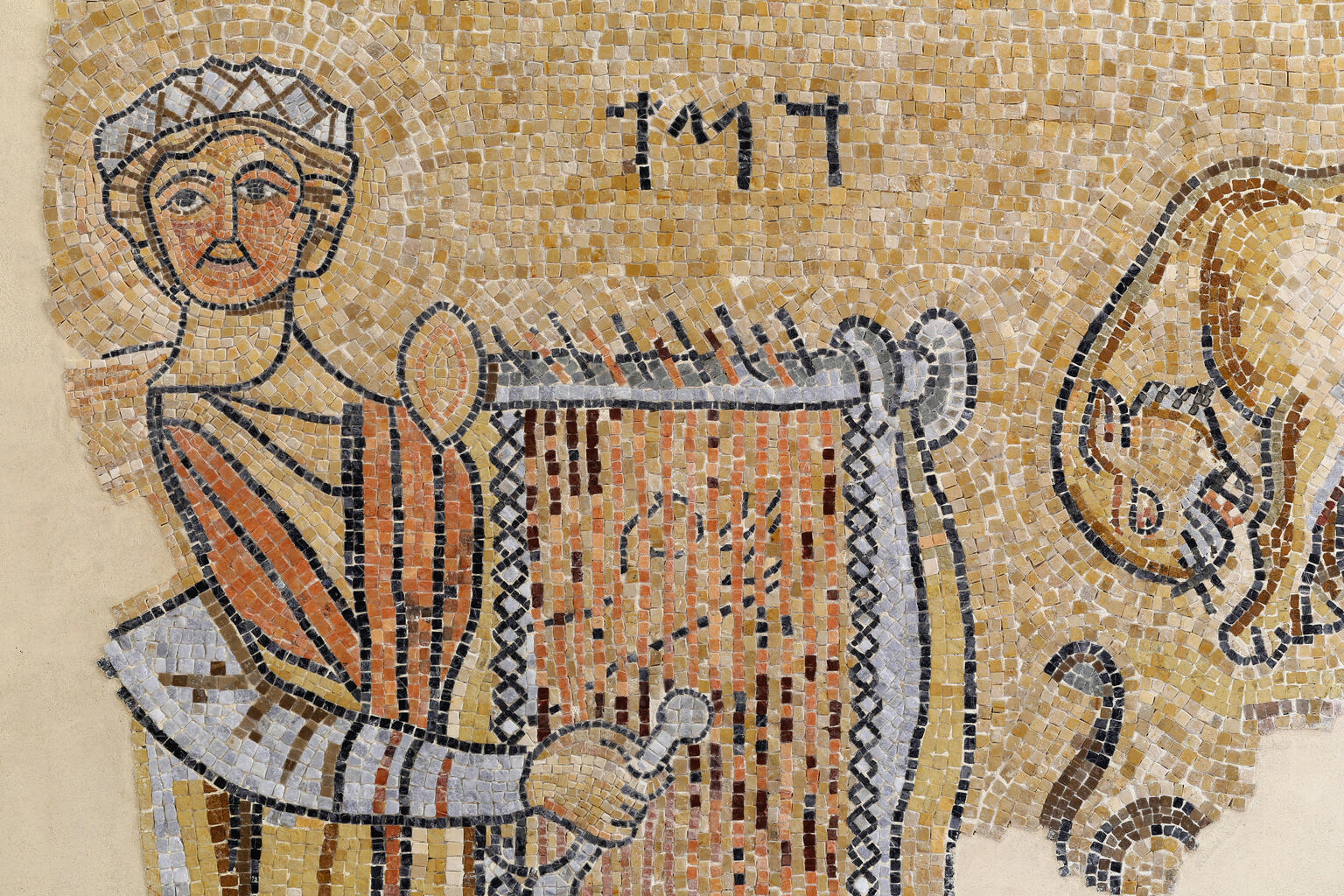 Ancient mosaic showing a person in a robe holding a lyre, with Hebrew letters above and part of an animal figure on the right side.