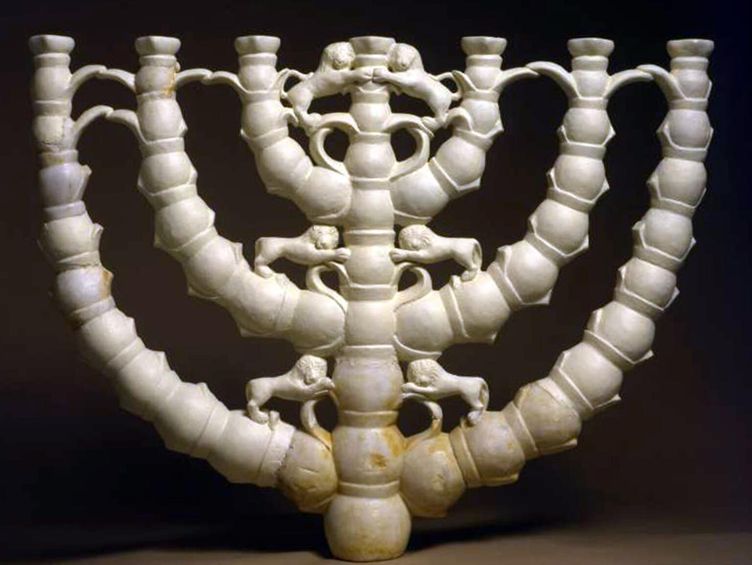 White menorah with seven branches, each decorated with lion figures and intricate connecting elements.