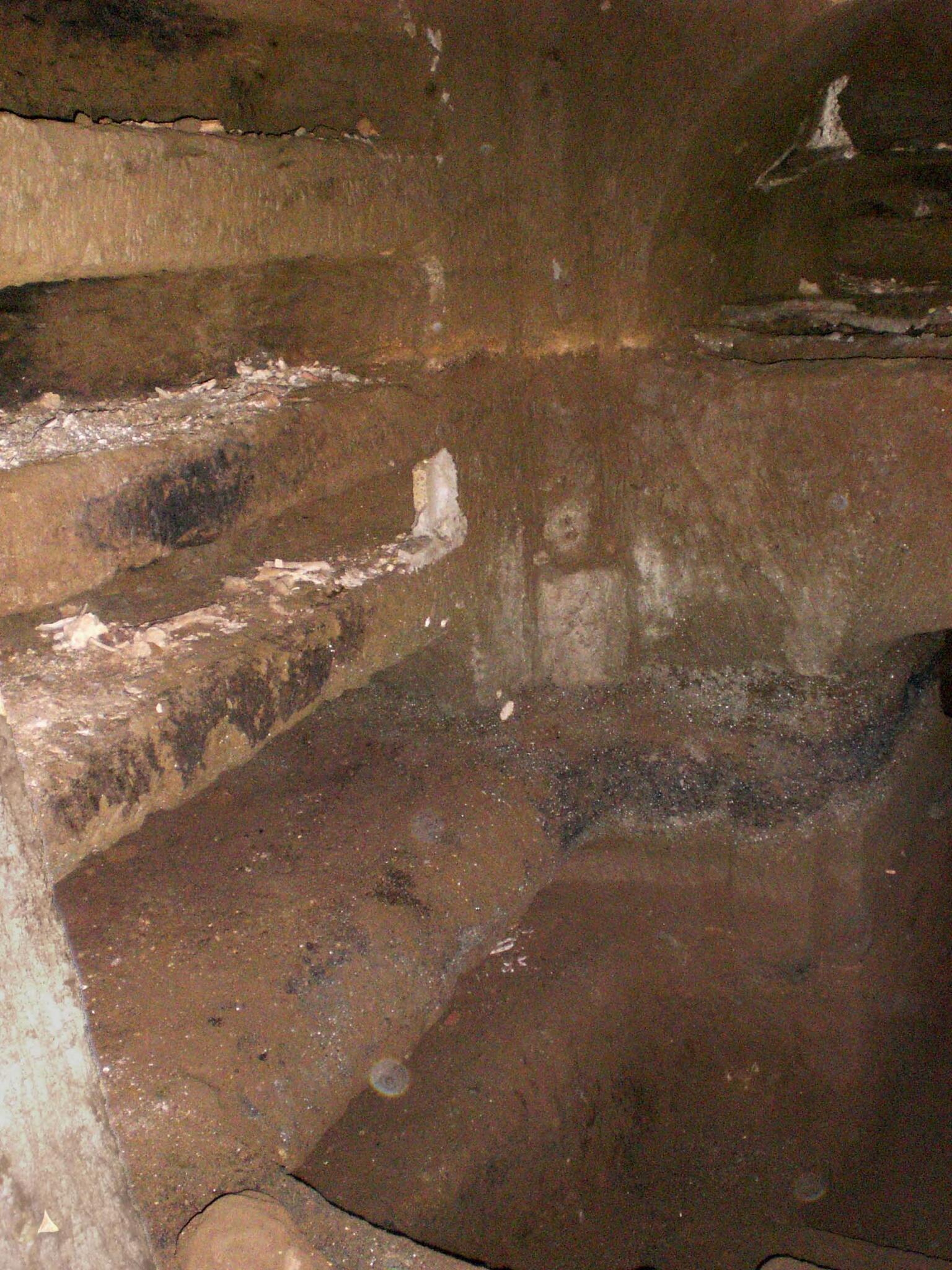 A stone chamber with carved shelves and niches along the walls, showing signs of age and wear.