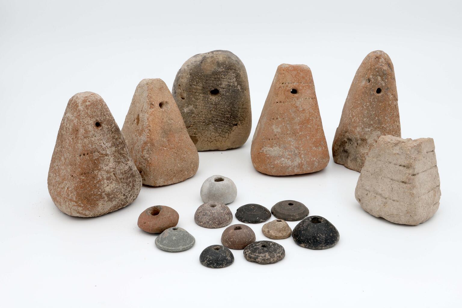 A group of ancient cone-shaped loom weights and disc-shaped spindle whorls with holes in the center.