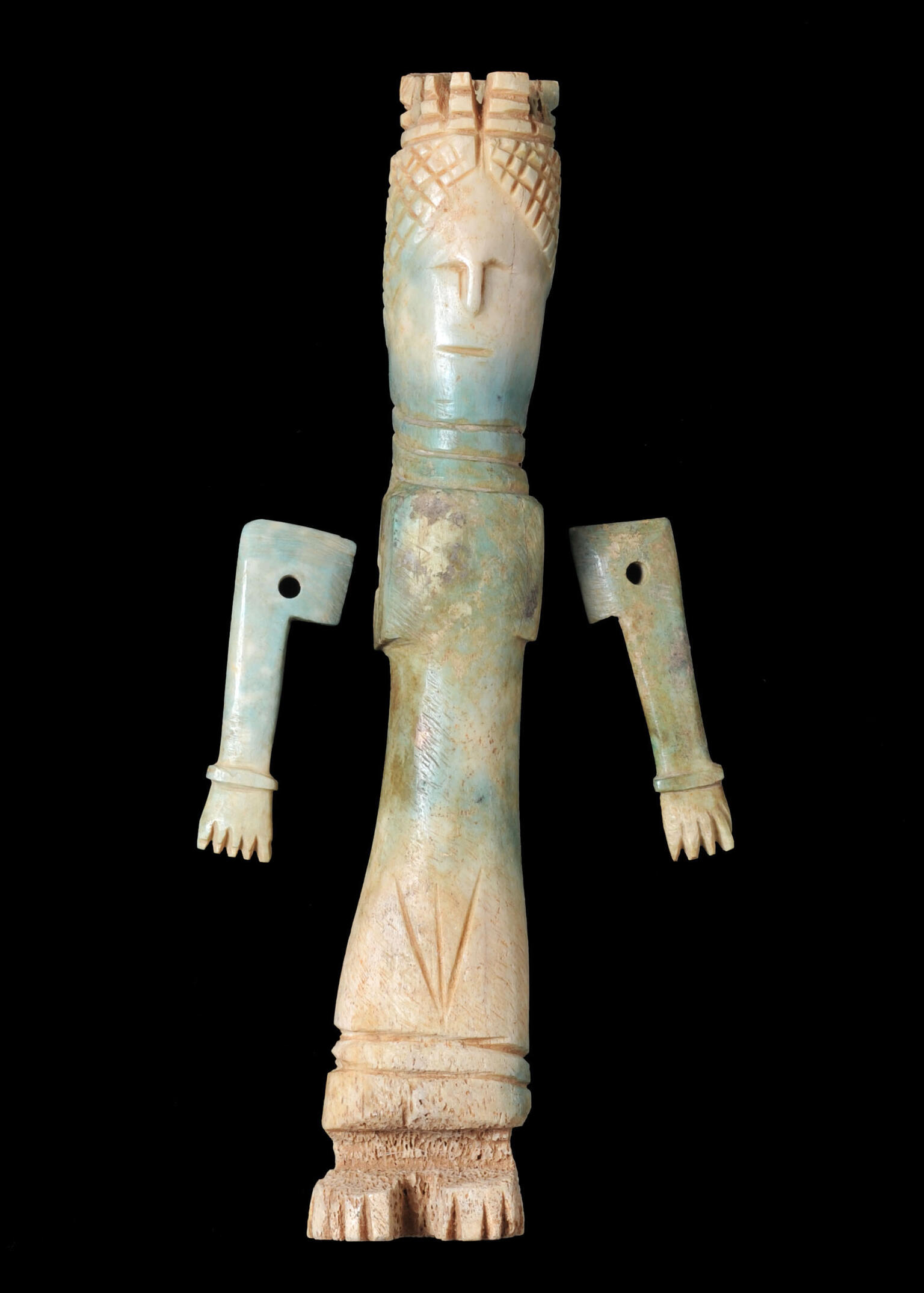 A carved bone figurine with a long body, stylized arms, a detailed headdress, and simple facial features.