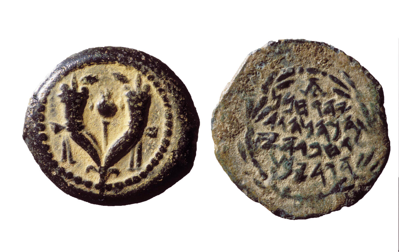 Two sides of an ancient coin: one side shows two joined cornucopias with a pomegranate in between, and the other side has an inscription in Paleo-Hebrew surrounded by a laurel wreath. The coin is aged and worn.
