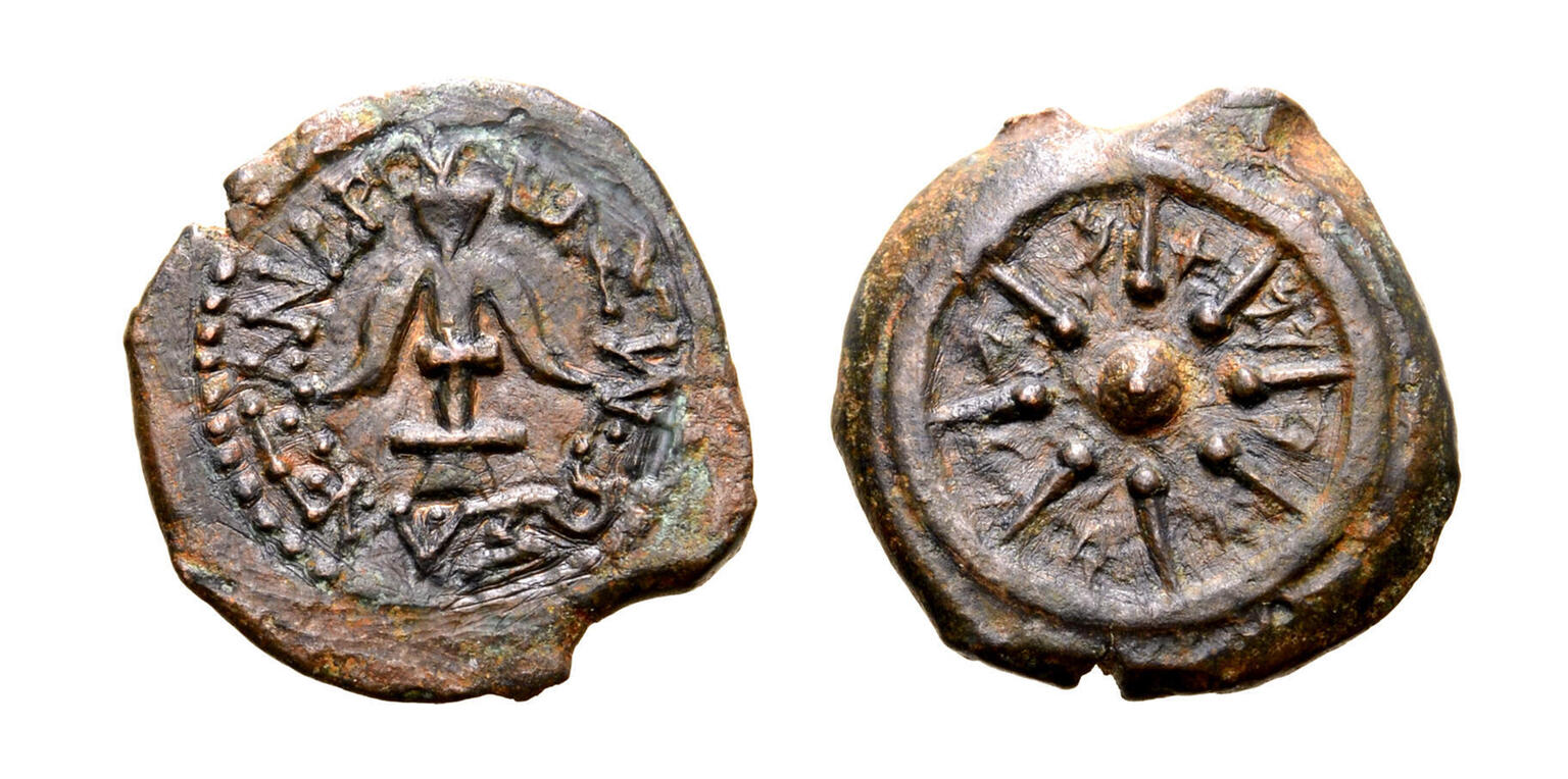 Two sides of an ancient coin: one side shows an anchor surrounded by a Greek inscription, and the other shows a small circle with eight rays radiating from it within a larger circle. Paleo-Hebrew letters are inscribed between the rays.