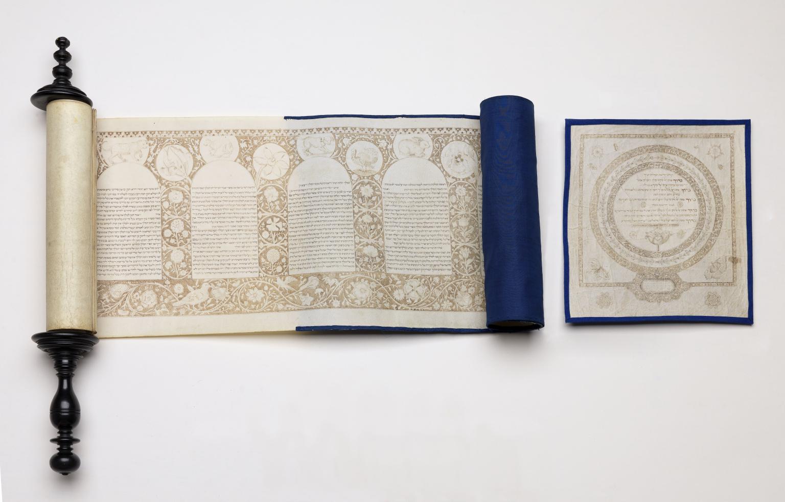 Partially unraveled scroll with Hebrew text in rounded columns and decorative border and individual page next to it with Hebrew text and circular border. 