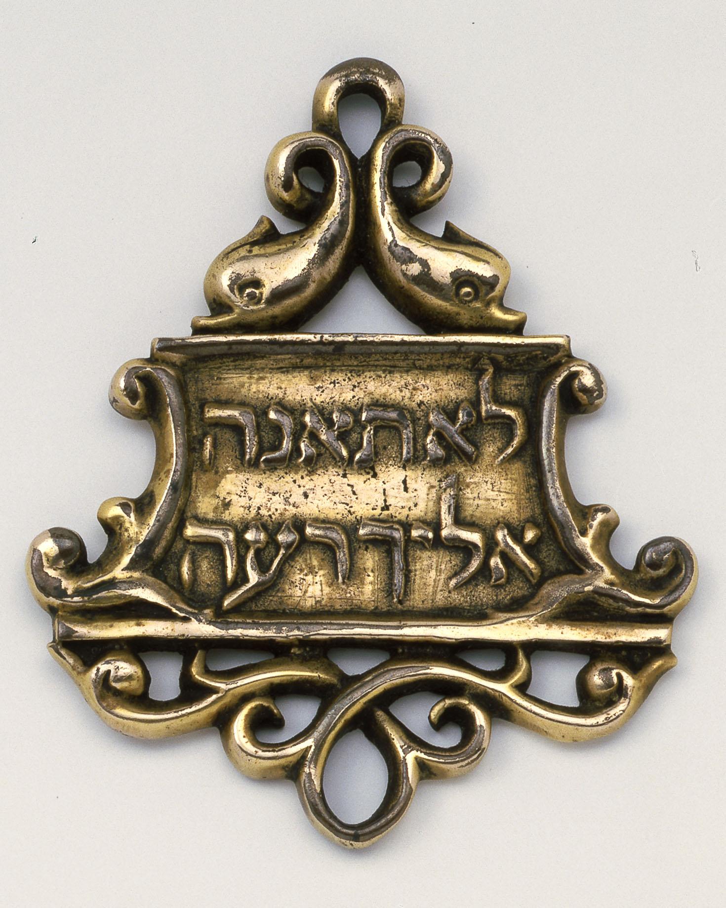 Bronze amulet with decorative border and Hebrew inscription.