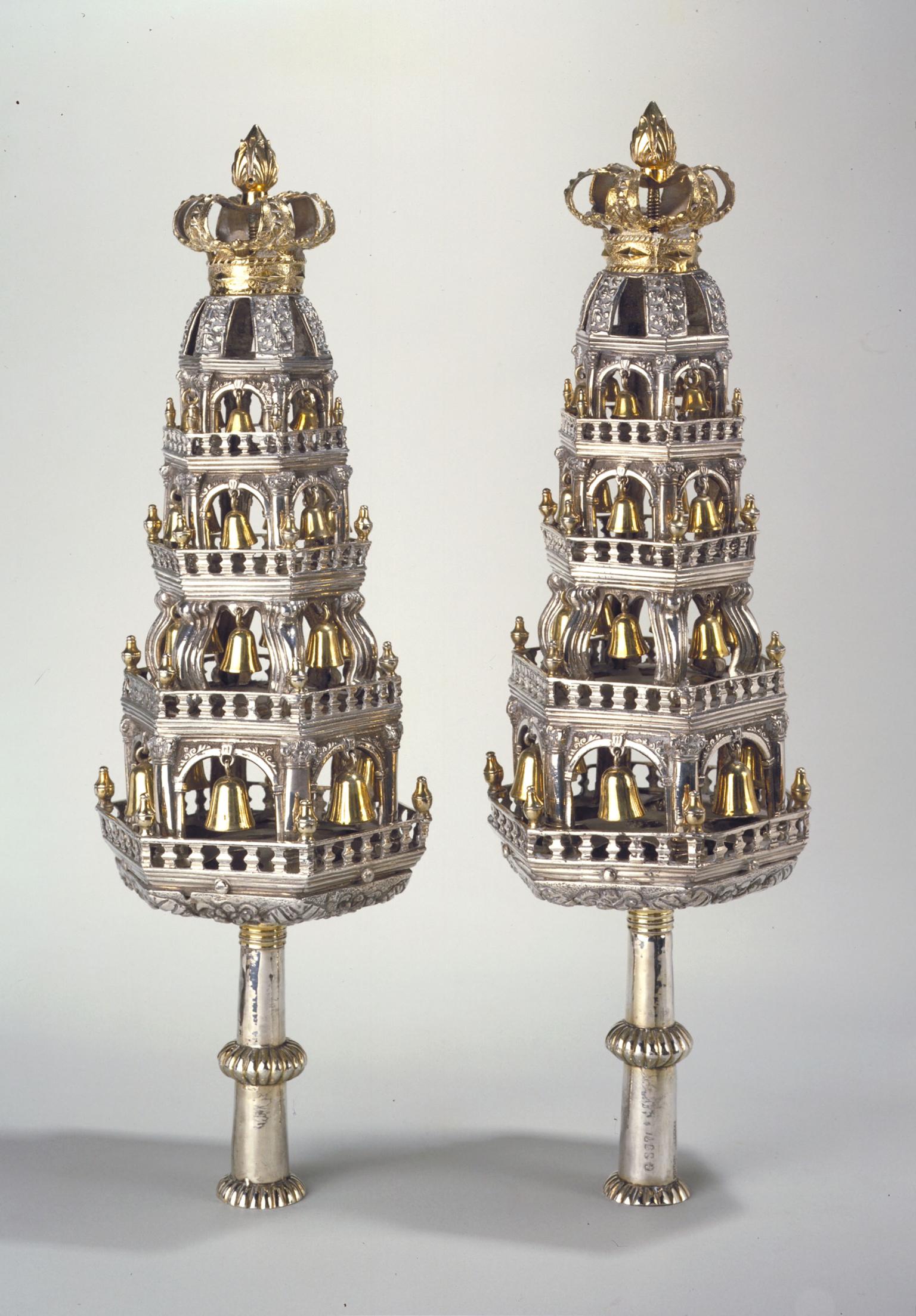 Pair of silver tower-shaped finials with crowns constructed like multitiered towers of arched cutouts decorated with bells. 