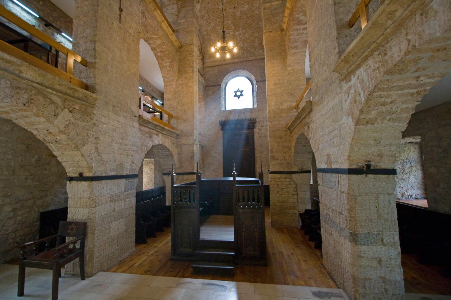 Photograph of room with arched stone doorways and central wooden platform. 