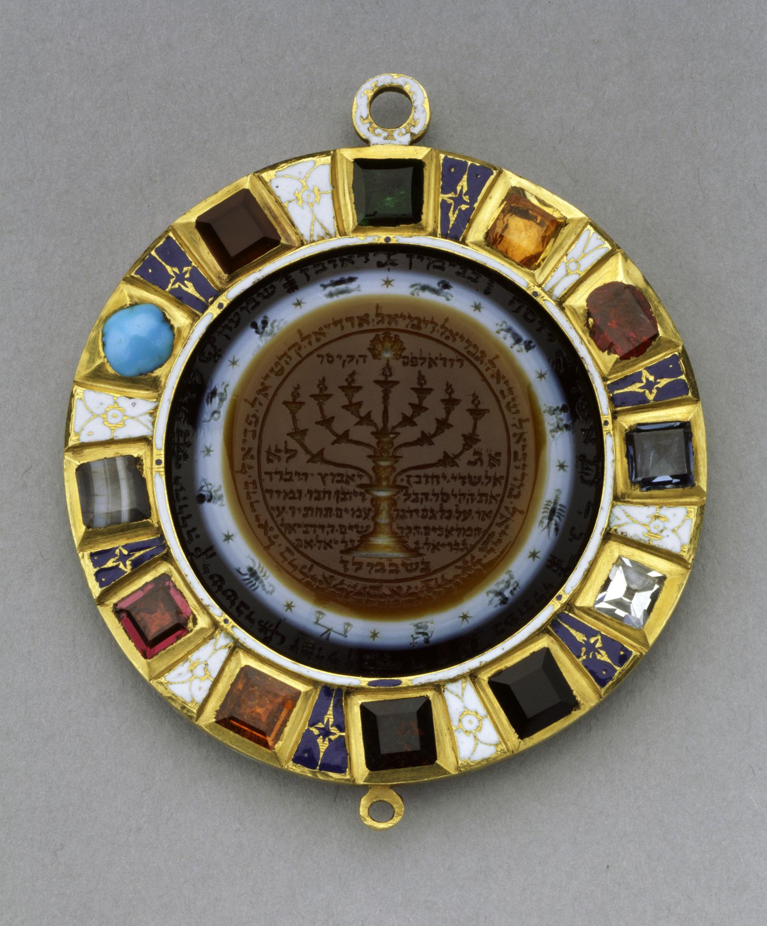 Circular amulet with stones around perimeter and image of candelabrum with Hebrew text in center, surrounded by images of the zodiac.