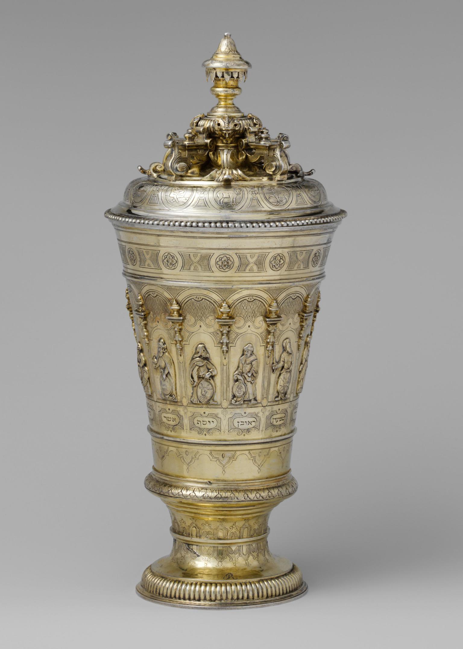 Silver cup with engraving of biblical figures along base and astrological figures and decorative designs on lid. 
