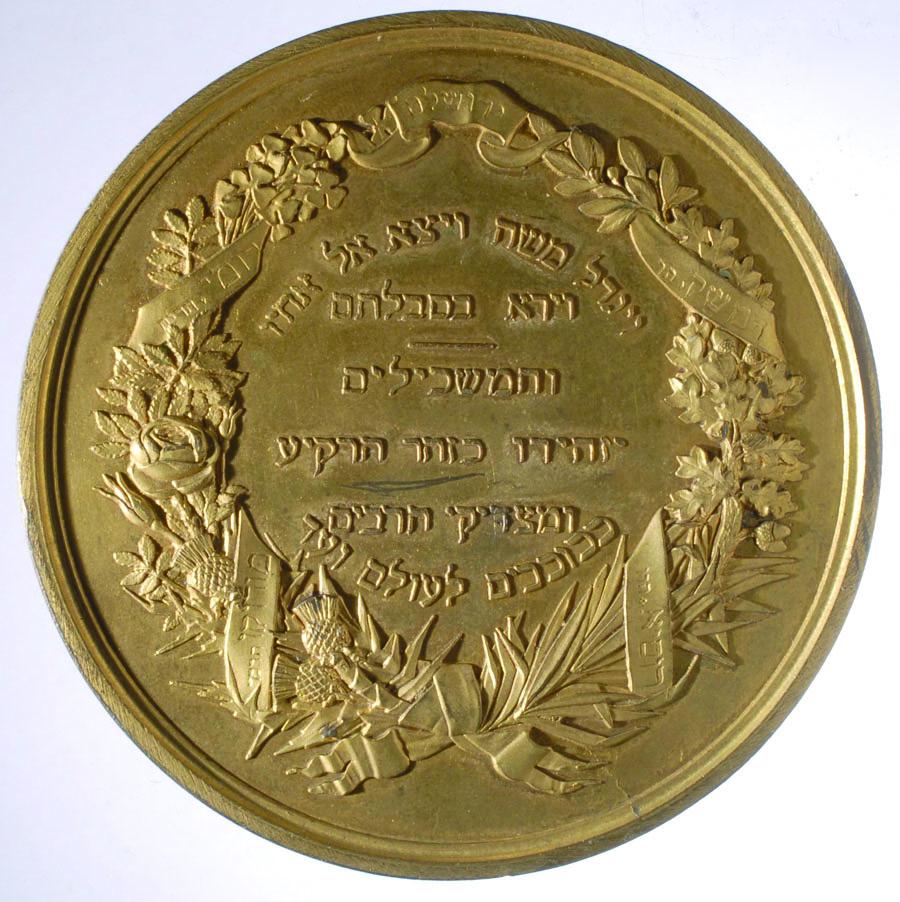 Medal with wreath border and Hebrew text inside.