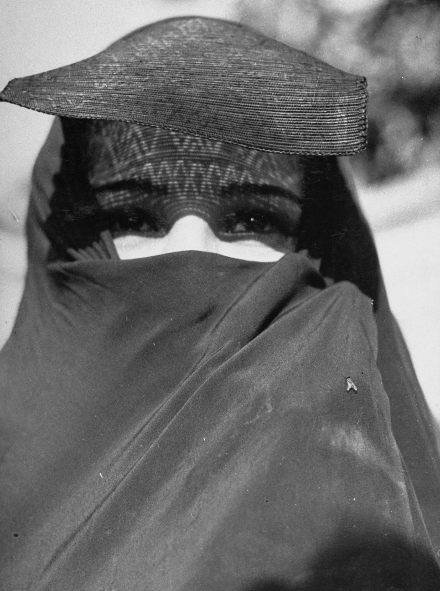 Photograph of veiled woman facing viewer with only her eyes exposed.
