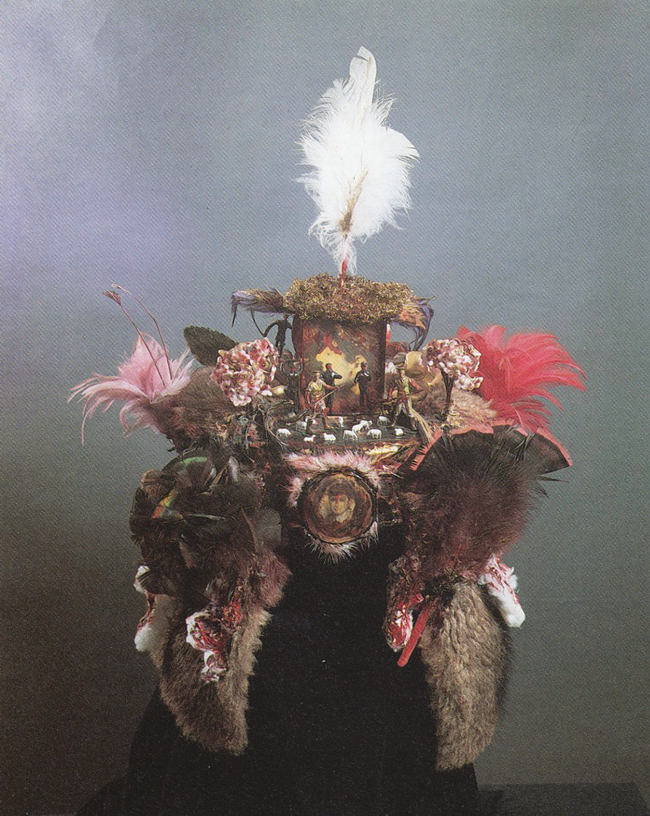 Assemblage of feathers, photographs, and figurines of humans and animals in a hat shape. 