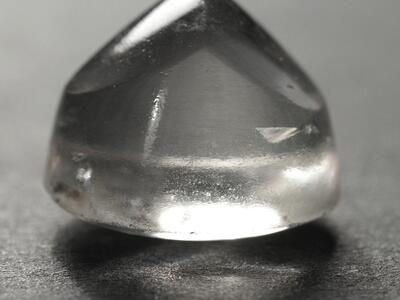 Photo of a transparent, slightly rough crystal piece with round bottom and crested top.