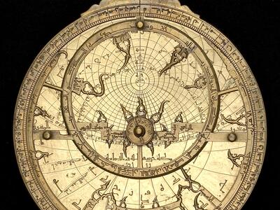 Ornate circular mechanical object with intricate Arabic inscriptions and geometric markings.