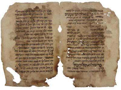 Facing, stained pages of handwritten Hebrew in two sizes, the smaller being vowelless.