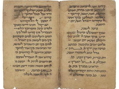 Facing manuscript pages in Hebrew script on lightly stained and damaged parchment.