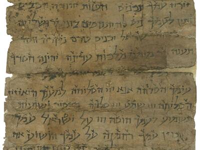Damaged, stained parchment filled with Hebrew writing with markings above.