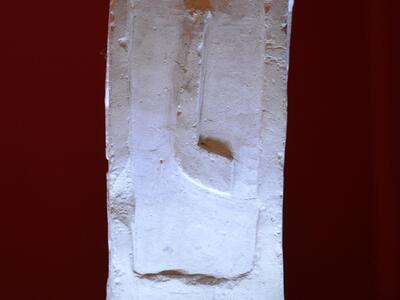 Photo of a weathered square stone slab inscribed with six lines of Latin.