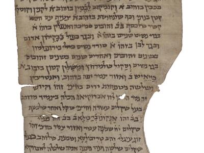 Damaged vertical parchment with Hebrew script conforming to its irregular shape, with the last line decorated with curls and a drawing of a candelabrum.