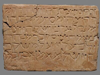 Rectangular brick tablet with six lines of carved Hebrew script and a broken upper-left corner.