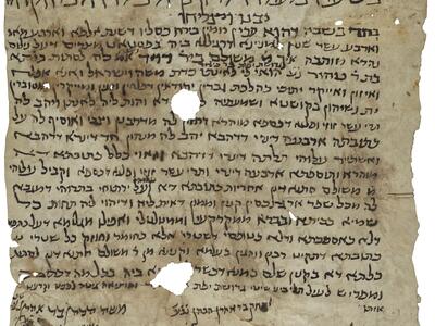 Damaged, stained parchment with vowelless Hebrew script, larger and decorated with floral elements at the top and in an irregular arrangement at the bottom, with two large and several small holes.