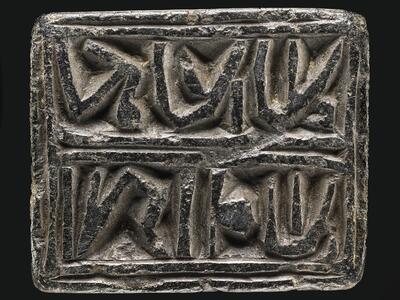 Photo of a rectangular black stone block inscribed with two outlined words of reversed Hebrew writing.