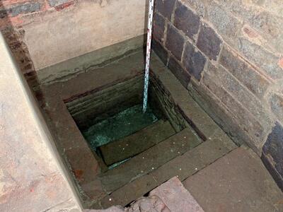 Photo of a square stone-and-brick-lined pool, with steps leading down.