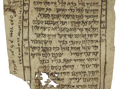 Damaged manuscript page with Hebrew script bordered by a simple frame, with additional text within and beside it.