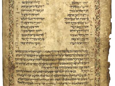 Damaged manuscript page with Hebrew in two columns followed by two paragraphs, surrounded by a colorful geometric and floral border, with smaller vowelless annotations beside the text and below the border.