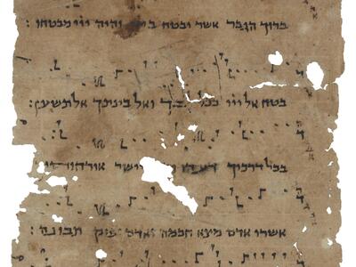 Damaged parchment page of Hebrew script with symbols above and between the lines.