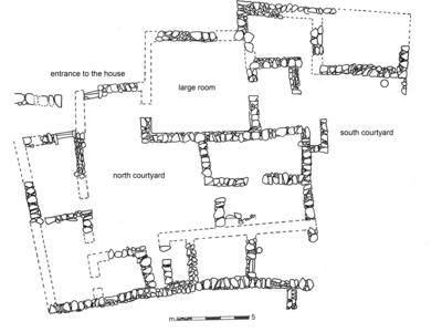 Black-and-white floor plan of an ancient house with labeled areas: entrance to the house, large room, north courtyard, and south courtyard. Stone wall outlines and a scale bar are shown.