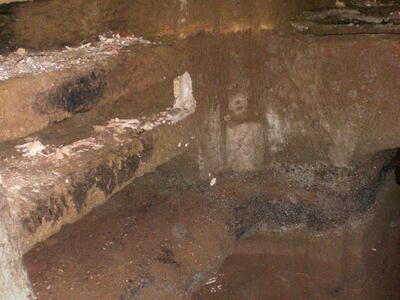 A stone chamber with carved shelves and niches along the walls, showing signs of age and wear.