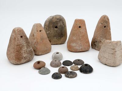 A group of ancient cone-shaped loom weights and disc-shaped spindle whorls with holes in the center.