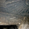 A stone ceiling with a large, fan-shaped relief carved into it, above a rough doorway in an ancient, dark stone chamber. The walls are textured and worn.