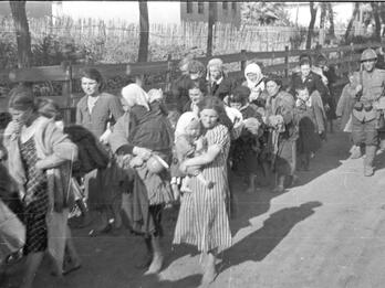 Photo of a line of Jewish women carrying children and belongings.