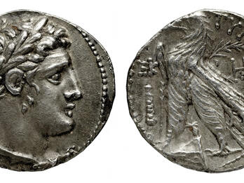 Ancient silver coin showing a laurel-wreathed profile on one side and an eagle standing on a thunderbolt with Greek inscriptions on the other side.