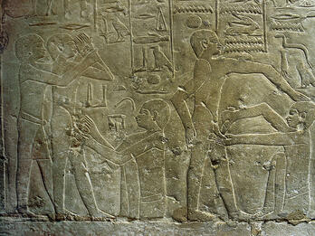 Circumcision in an Egyptian Relief Relief with hieroglyphs above standing figures while others sit and perform circumcisions.