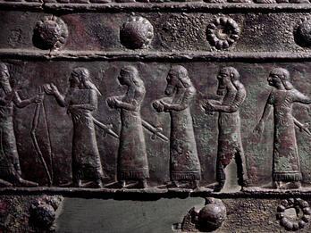 Relief of many figures in a row, some of whom are naked with hands tied behind their backs.