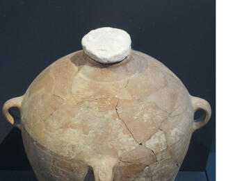 Large clay storage jar with stopper in neck and handle stamped with Hebrew letters.