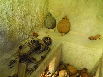 Burial Chamber from Ketef Hinnom Cemetery Interior room with ledges, one of which holds a skeleton, and a floor covered with pottery.