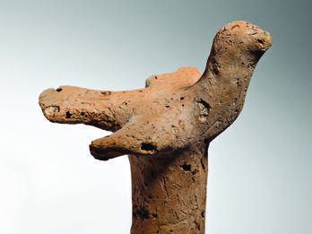 Terra-cotta bird figurine with outstretched wings on pillar.