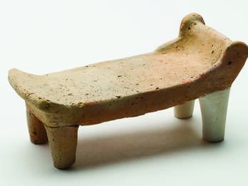 Model Bed Terra-cotta bed with headrest and footrest standing on four legs.