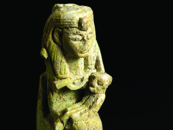 Faience amulet with Egyptian goddess wearing headdress sitting on a throne and holding a child.