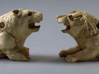Crouching Ivory Lion Figurines Two ivory lion figurines with open mouths and small holes throughout.