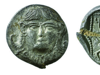 Front and back of coin, with image of face on front of coin and lion, bovine, and Hebrew inscription on back.