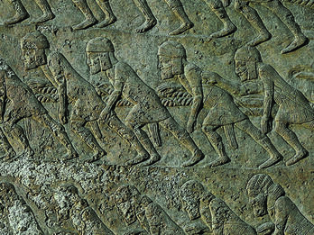 Judahite Captives among the Builders of Sennacherib’s Palace Wall relief showing workers wearing tunics, caps, and sashes, harnessed by shoulder straps to ropes and leaning forward.