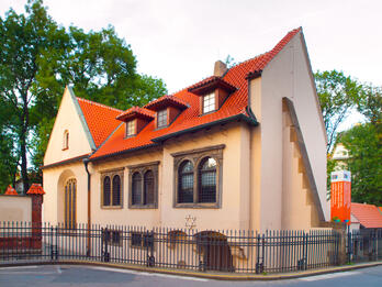 Pinkas Synagogue Front view of building exterior with curved tile roof and arched windows and metal fence around perimeter.